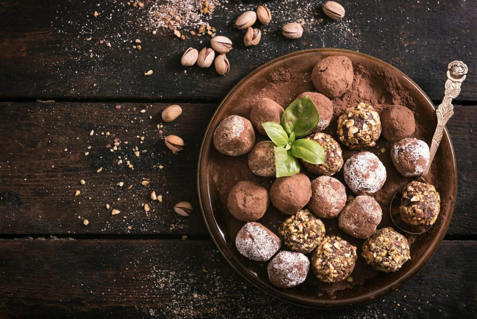 A bowl of nuts and chocolate truffles on a table.