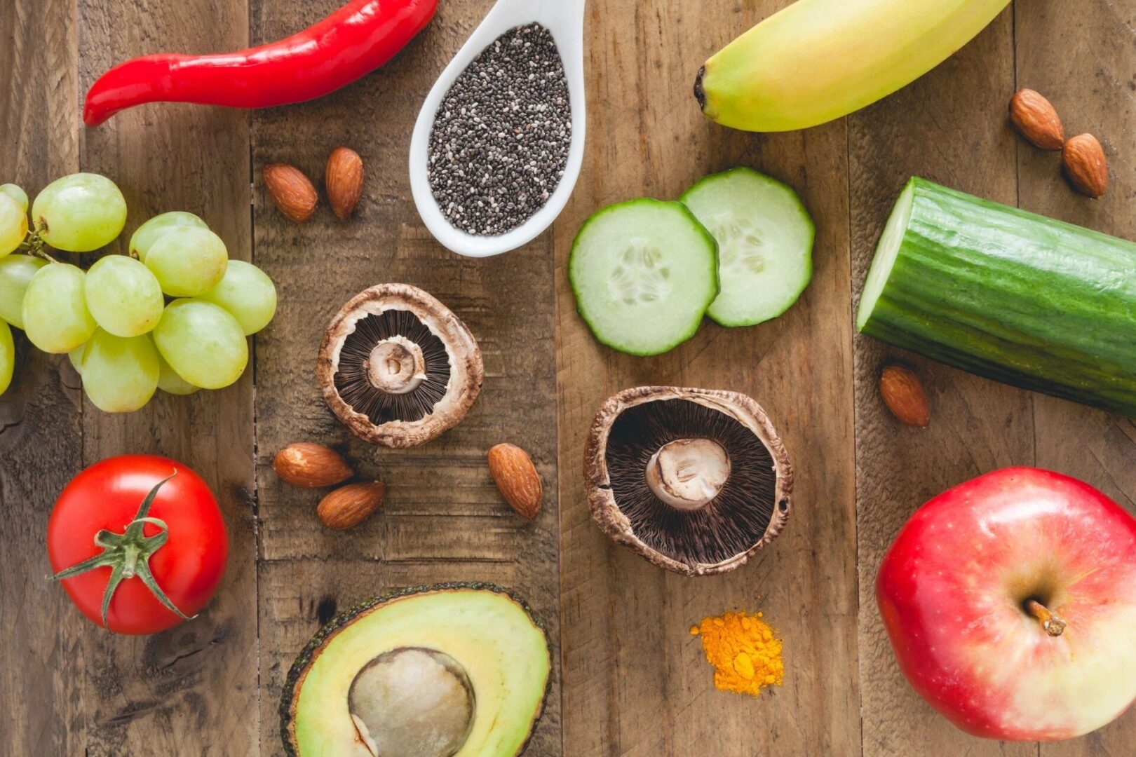 A wooden table topped with lots of different fruits and vegetables.