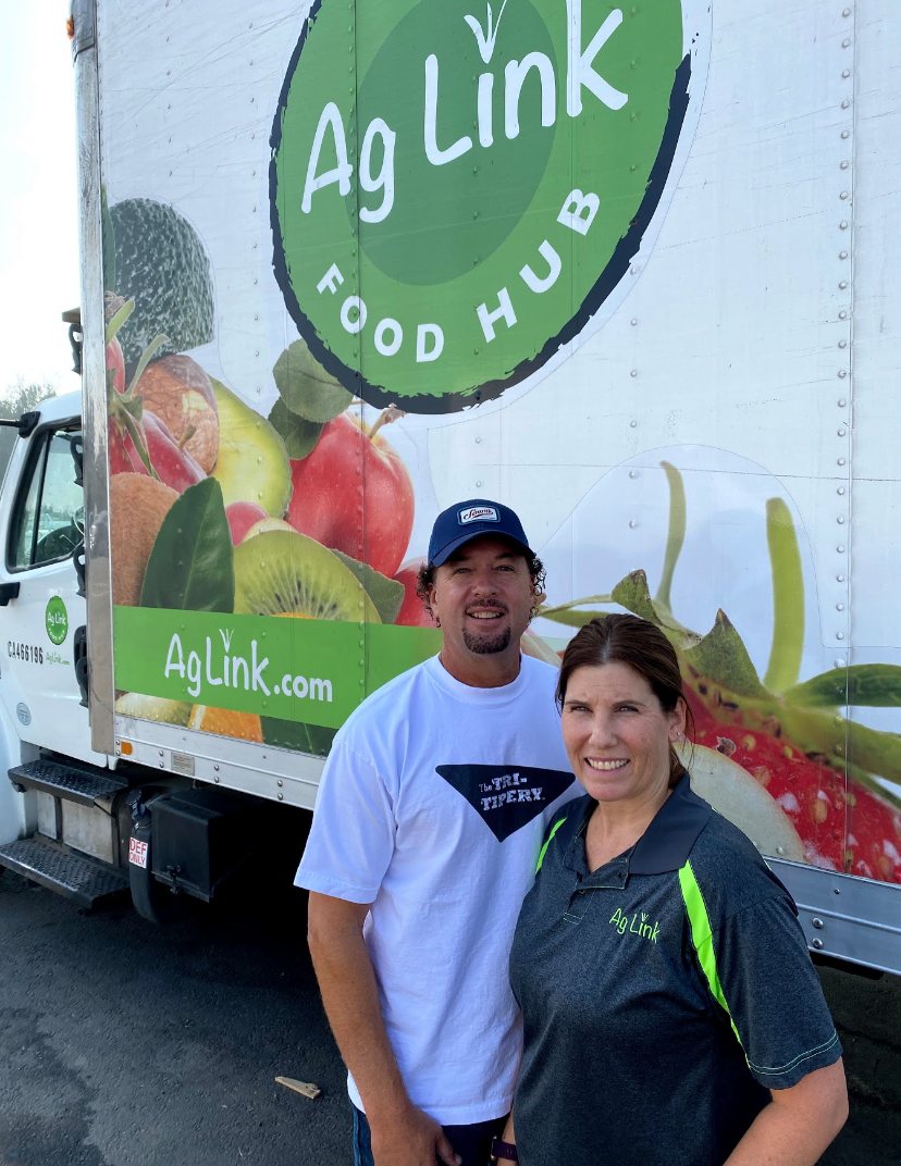 A couple standing in front of a truck.