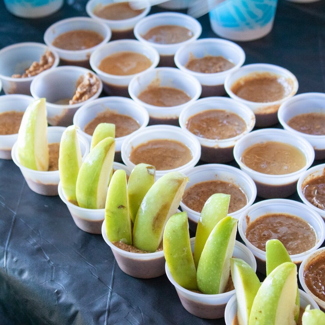 A table topped with cups of food and bananas.