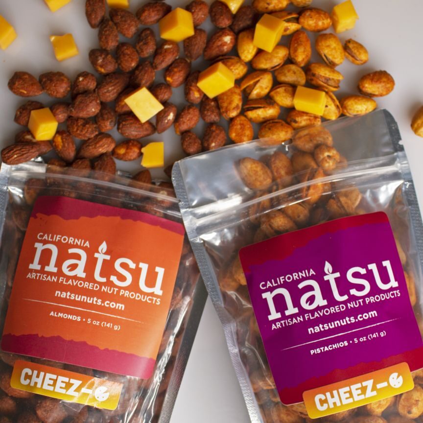 Two bags of natsu cheez-e are sitting next to a pile of corn kernels.