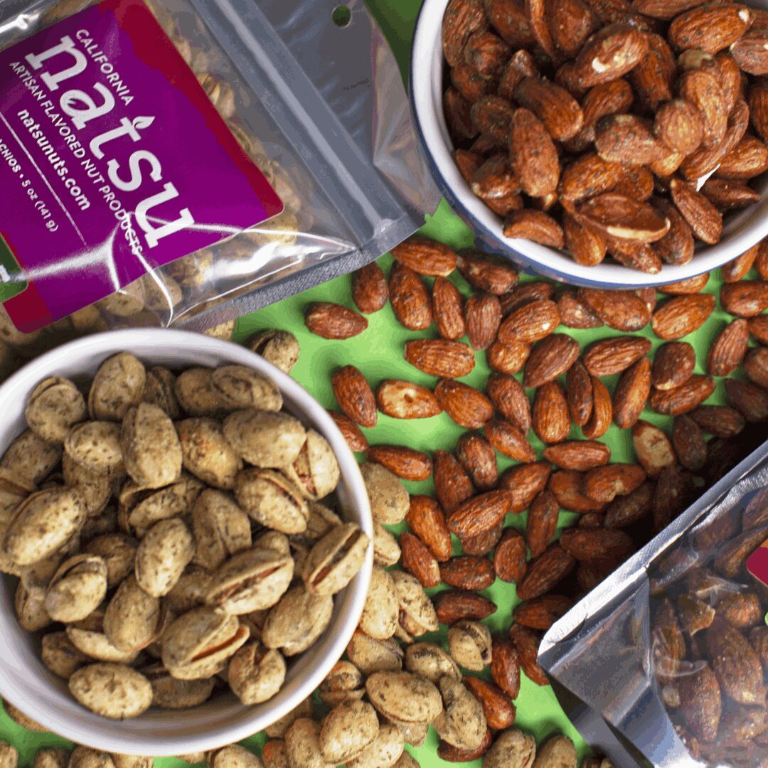 Nuts are in bowls on a table with other nuts.