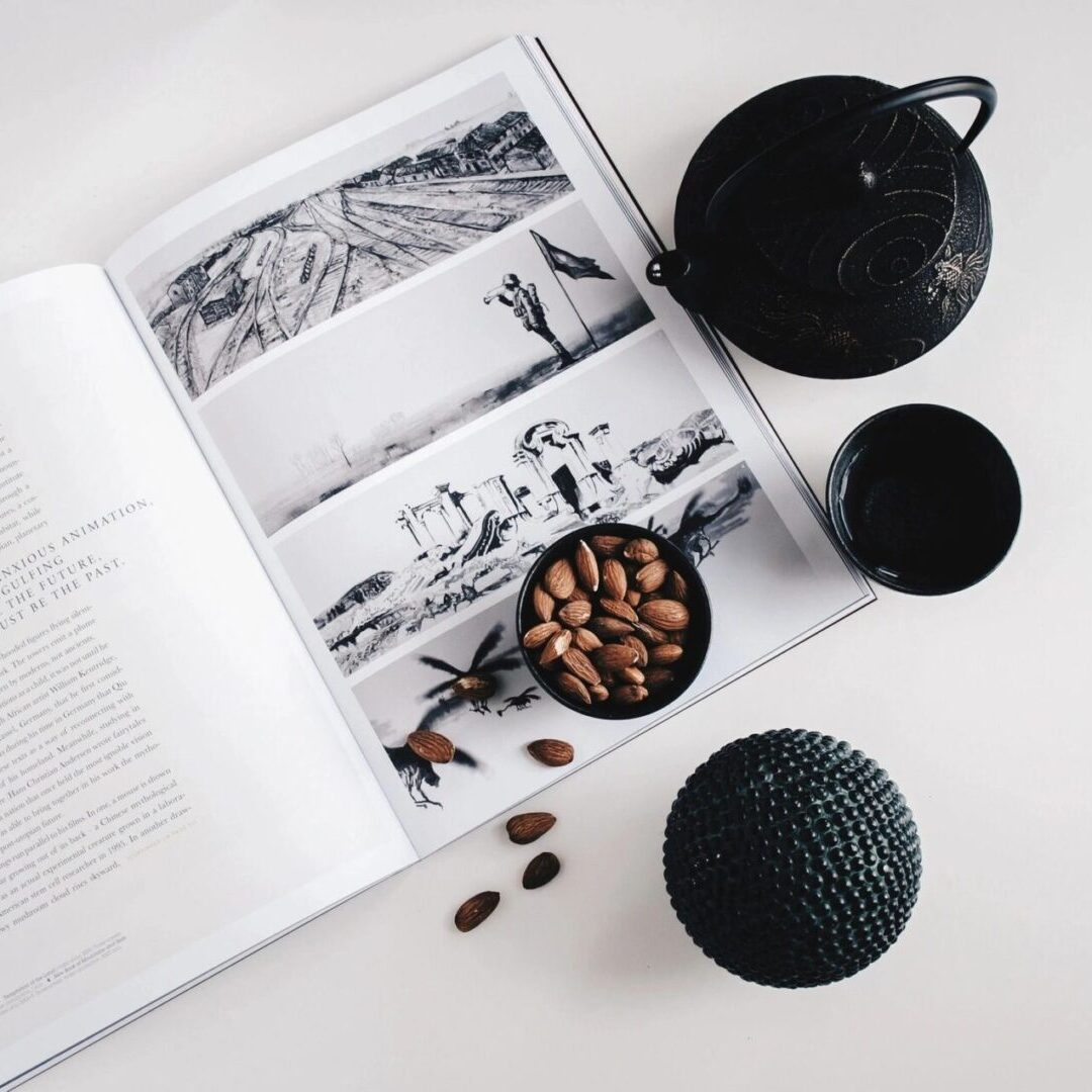 A book with coffee beans and two cups on the table.